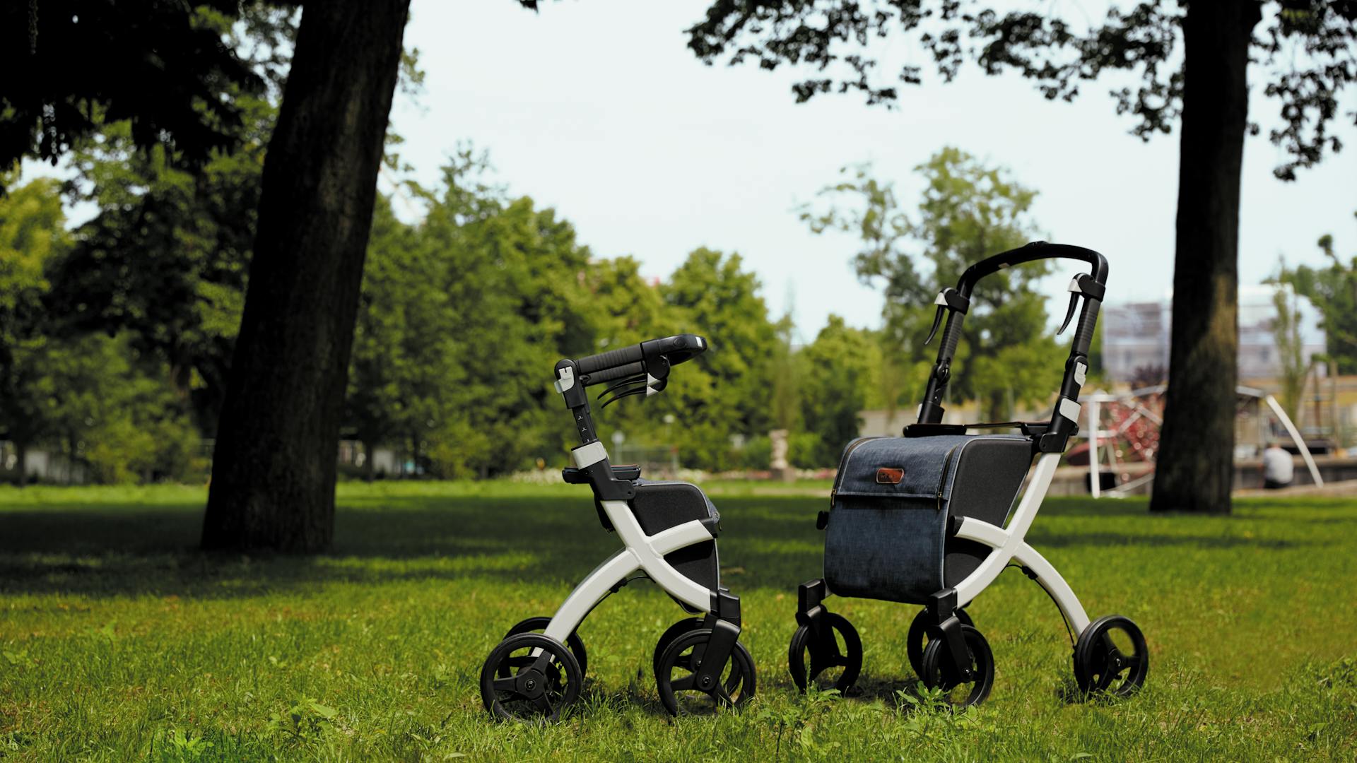 Two modern rollators parked on green grass in a sunny summer park setting